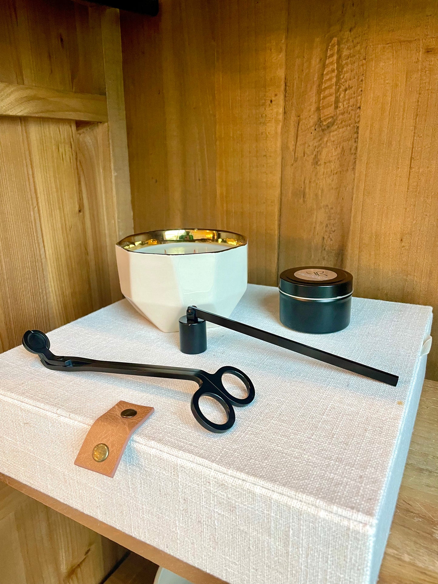 High Maintenance Gift Set featuring our full sized candle in a white asymmetric vessel. It also has our mini travel sized candle. Along with our candle accessories which includes a set of the candle wick snuffer in either black, gold, or silver